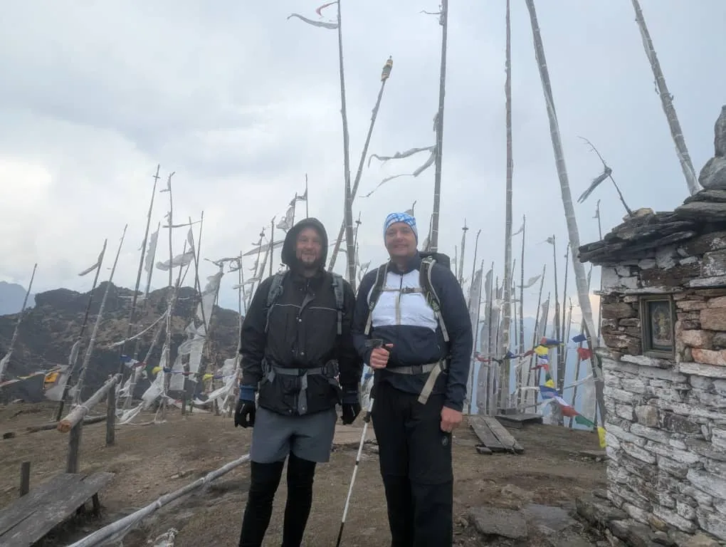 Two trekkers among tall white prayer flags at the sky burial site above Bumdra