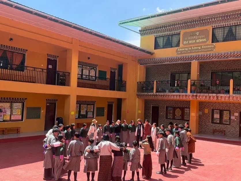 ELC students crossing the red courtyard between the yellow school buildings
