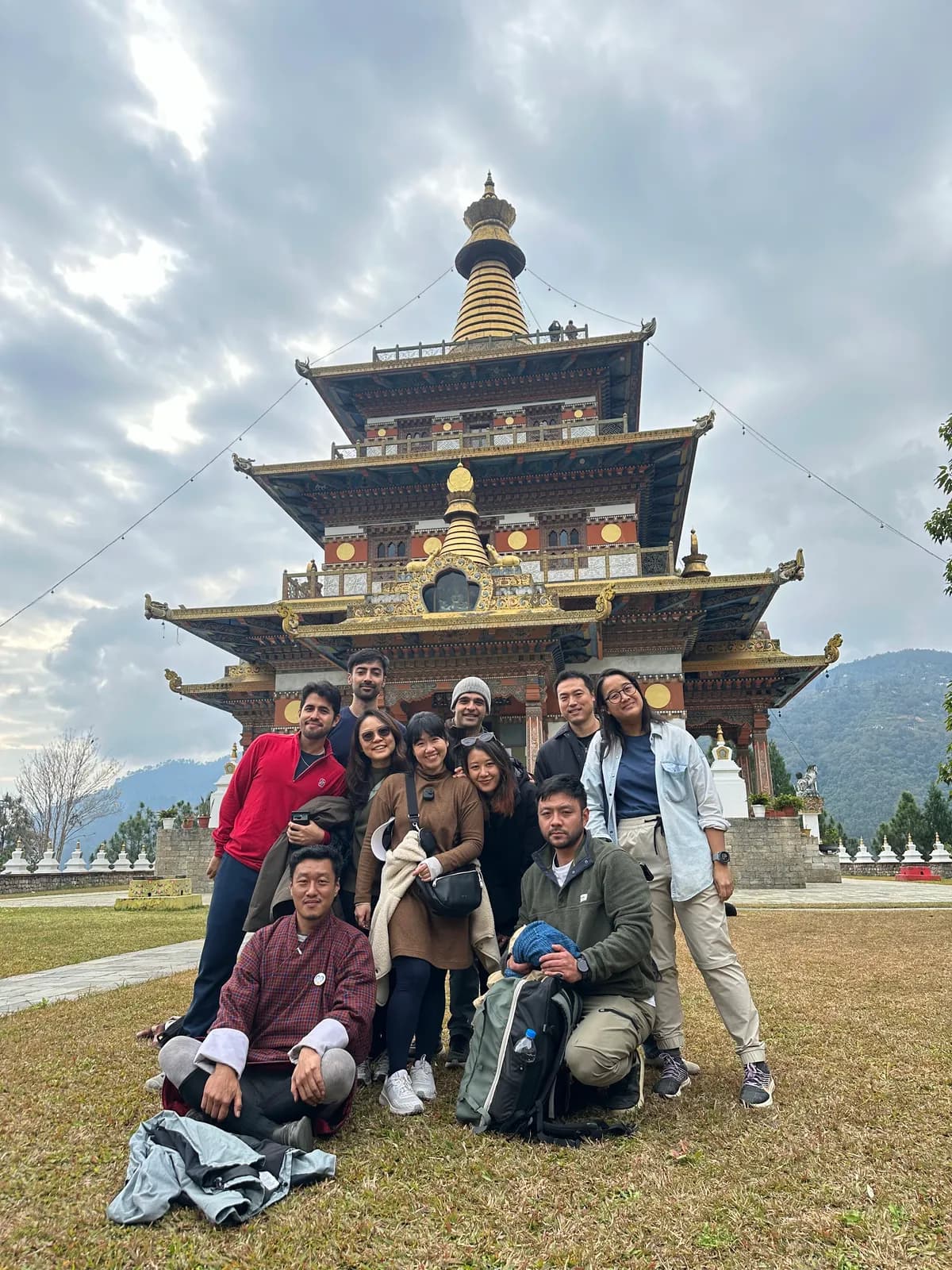 A group photographed at the foot of Khamsum Yulley Namgyal Chorten, its tiers rising behind them