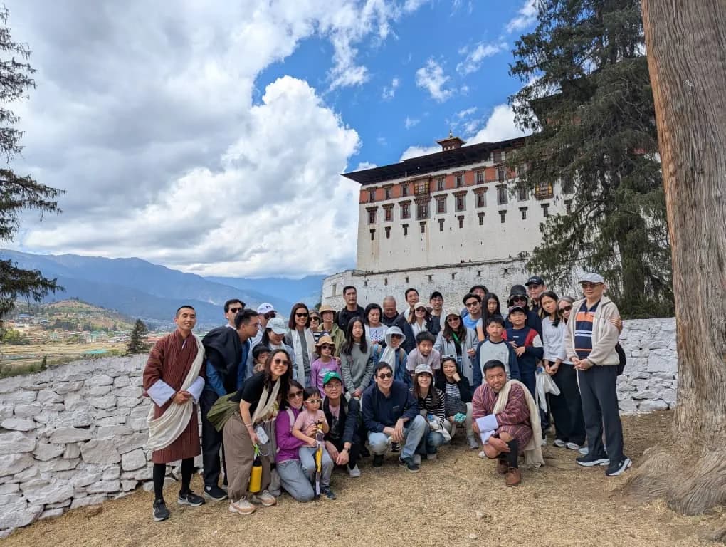 A large group gathered on the wall below the white face of Paro Dzong