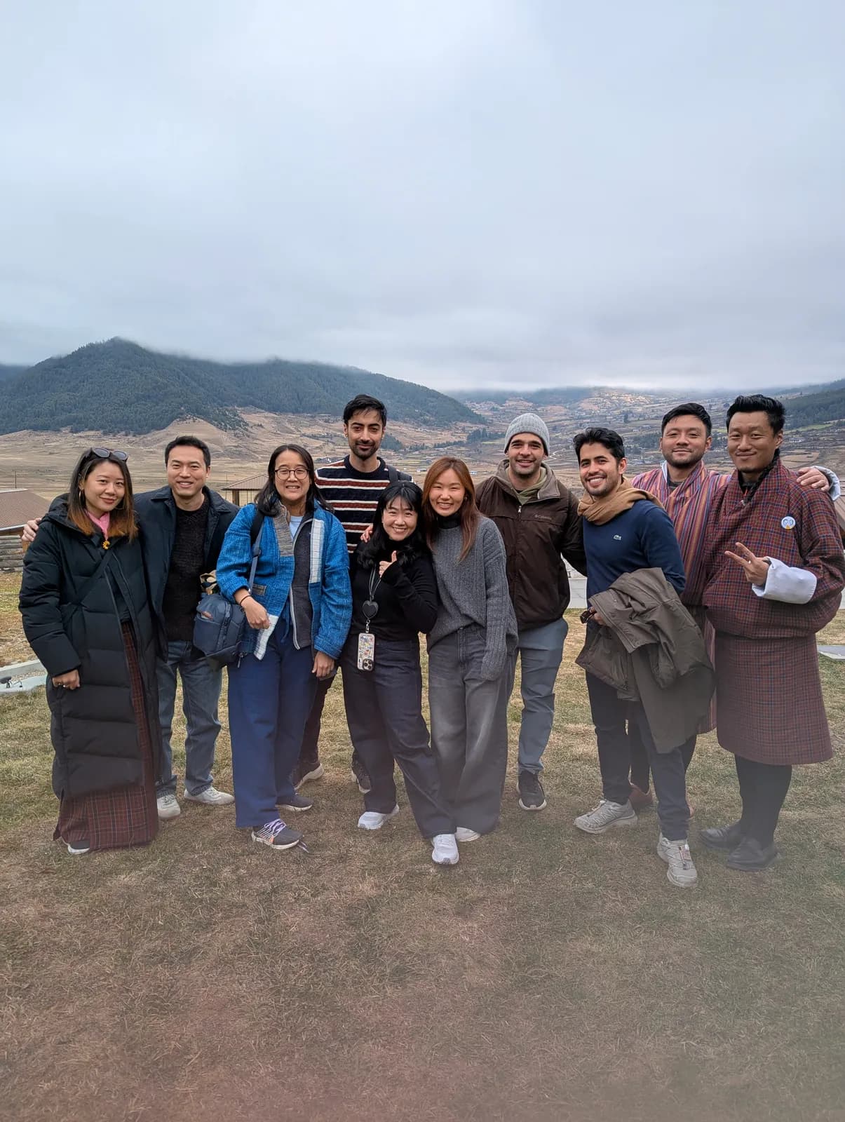 A group standing together on the open floor of the Phobjikha valley on a gray morning