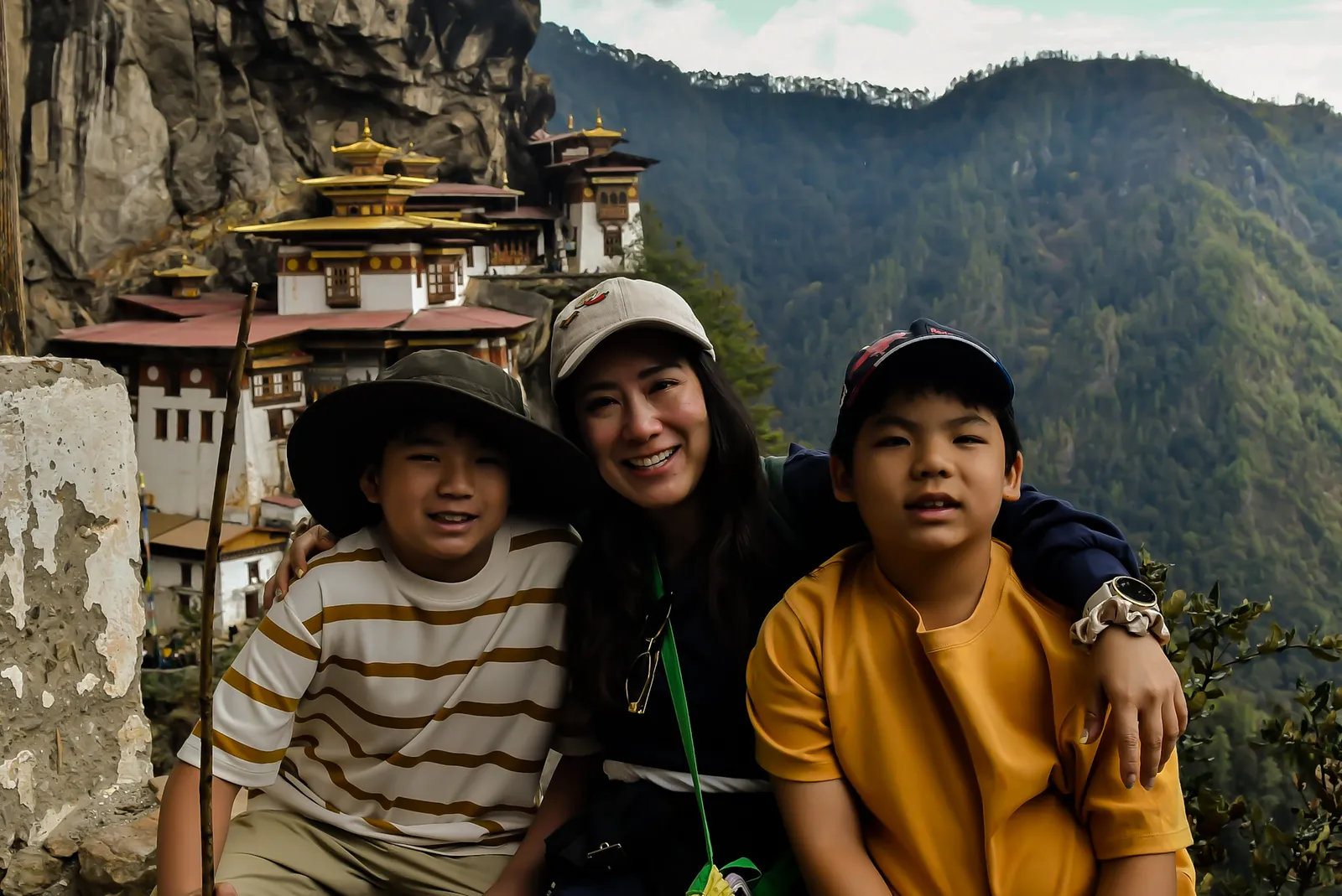 A mother and two children on the trail, Taktsang Monastery on the cliff behind