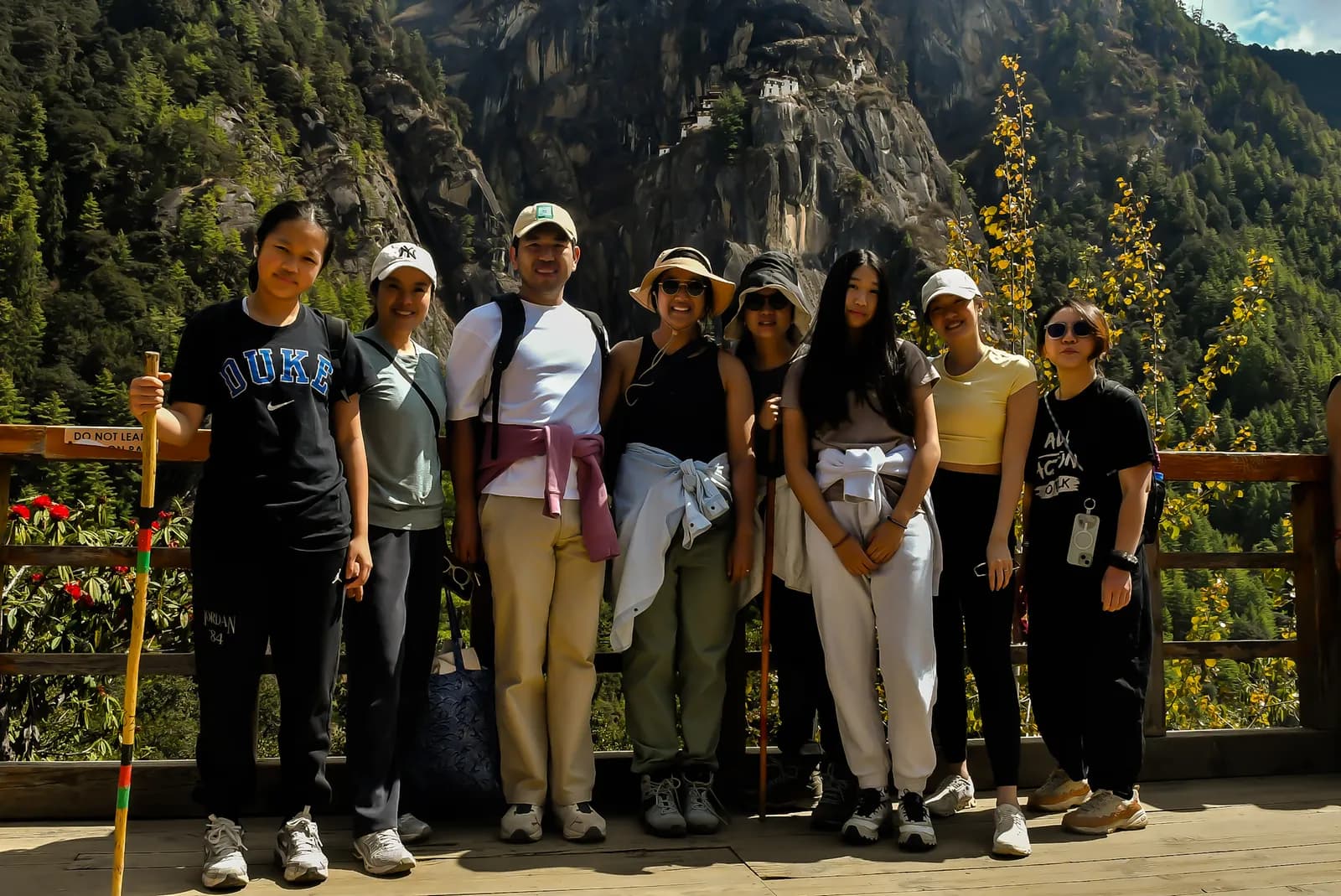 A group at the viewing platform across from Taktsang, the cliff face behind them