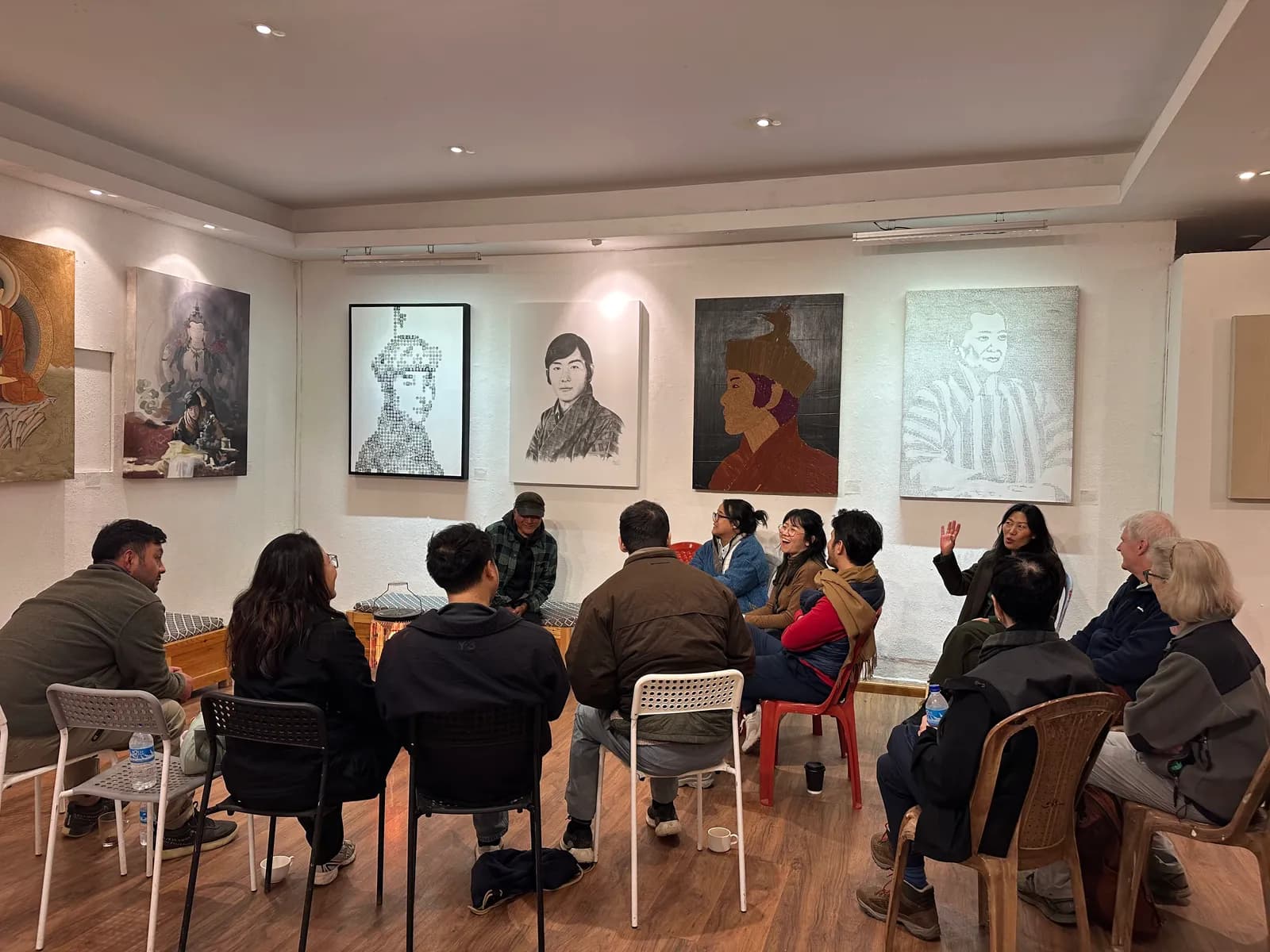 A circle of visitors seated among paintings at the VAST studio in Thimphu, listening to the founder