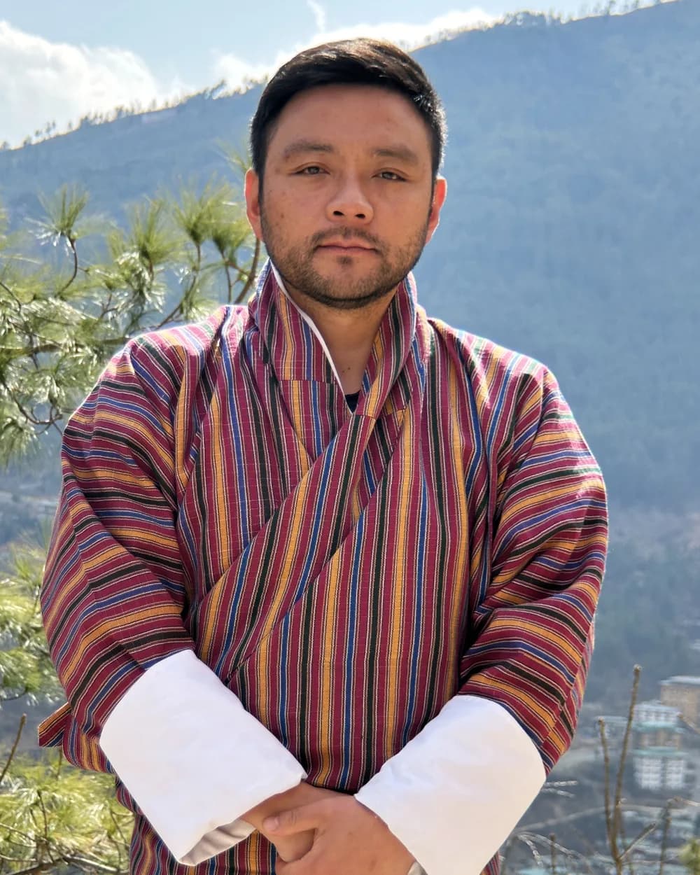 Jambayang Wangchen Tshering in a striped gho, on a terrace above the Thimphu valley