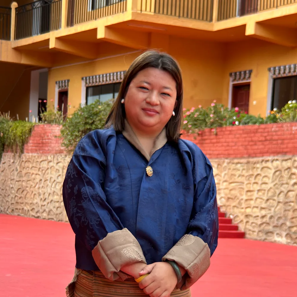 Karma Phuntsho Wangmo in a blue silk kira jacket, in the school courtyard