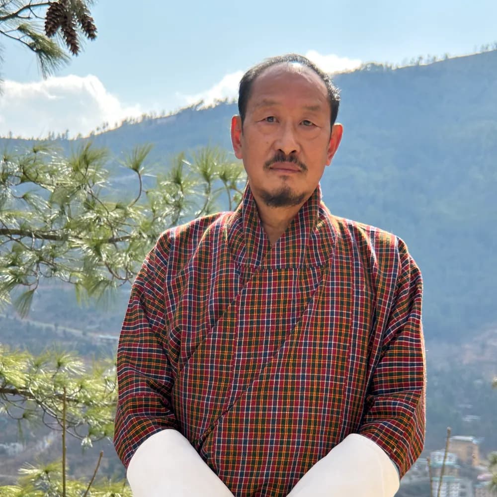 Kinzang Namgay in a checked gho, on a terrace above the Thimphu valley