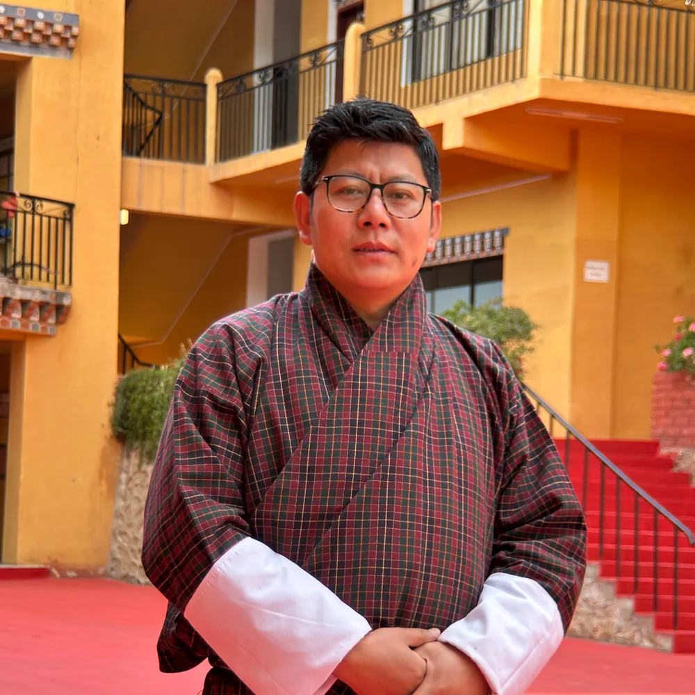 Tshewang Loday in a maroon checked gho, in the school courtyard