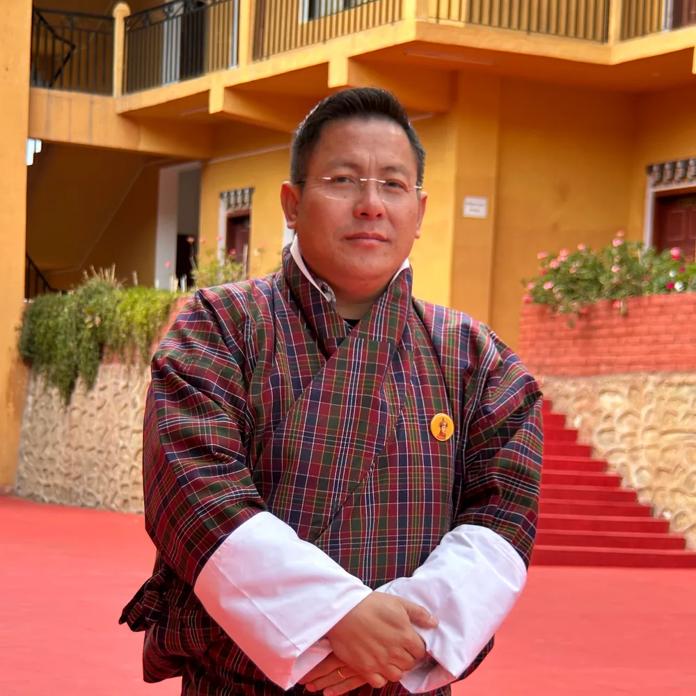 Yonten Nidup in a checked gho, in the school courtyard