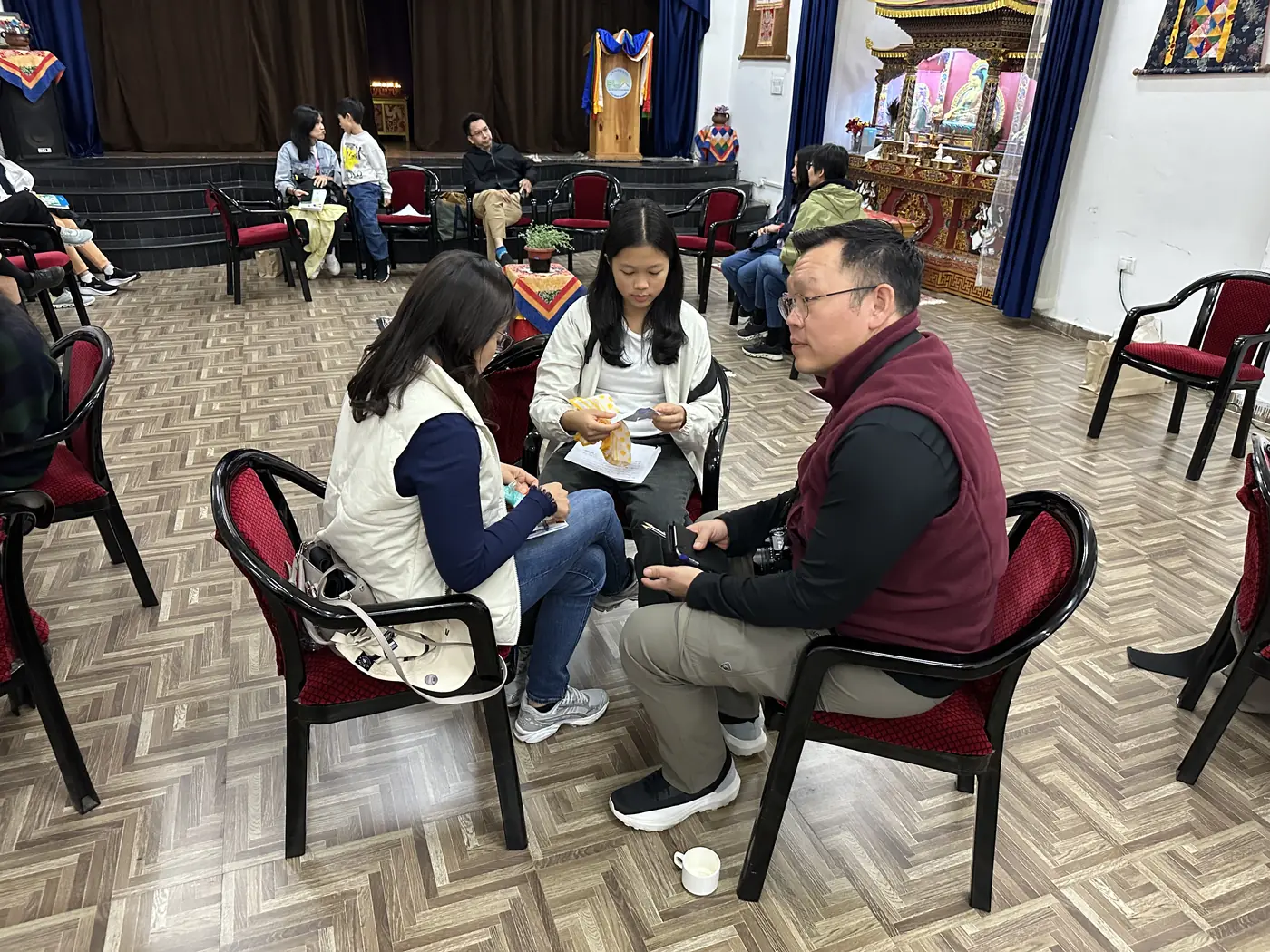 Parents and teachers talking in small groups of three in the school hall during a family wellbeing session